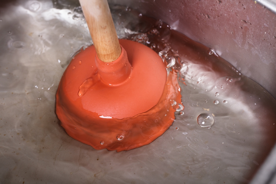 An Orange Cup Plunger In The Washbasin Filled With Water.