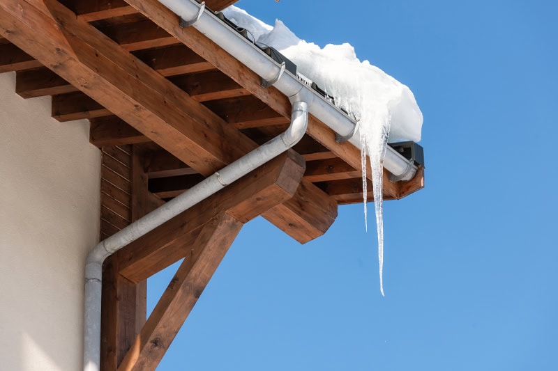 A big icicle hanging from a roof.