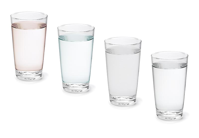 Four drinking glasses filled with liquid are arranged in a diagonal line against a plain white background.