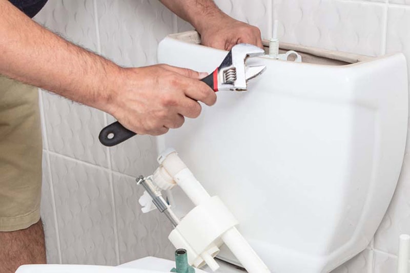 Why Is My Toilet Bubbling? What It Means and What You Should Do. A repair man fixing a toilet.