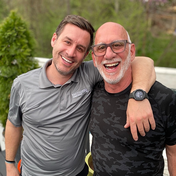 Tony & Matt LaMartina outside and smiling against a wooded backdrop.