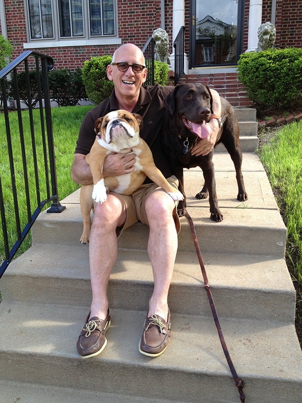 Tony LaMartina sitting on steps outside of a house with two lovable dogs.